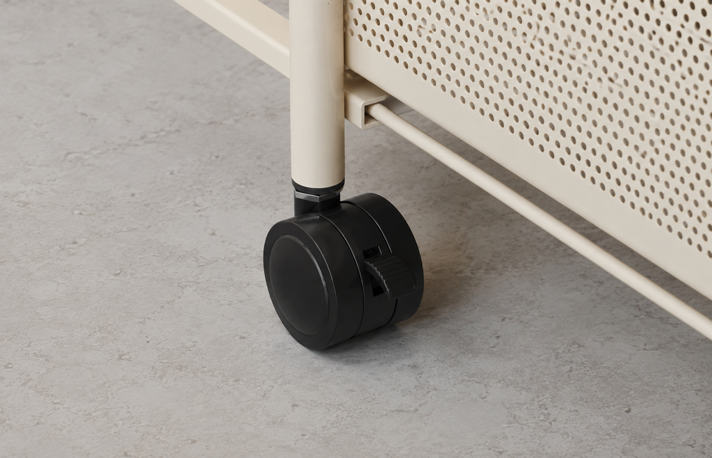 Close-up of a black caster wheel attached to a cream-colored metal frame, set on a gray concrete floor.
