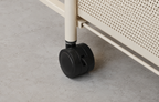 Close-up of a black caster wheel attached to a cream-colored metal frame, set on a gray concrete floor.